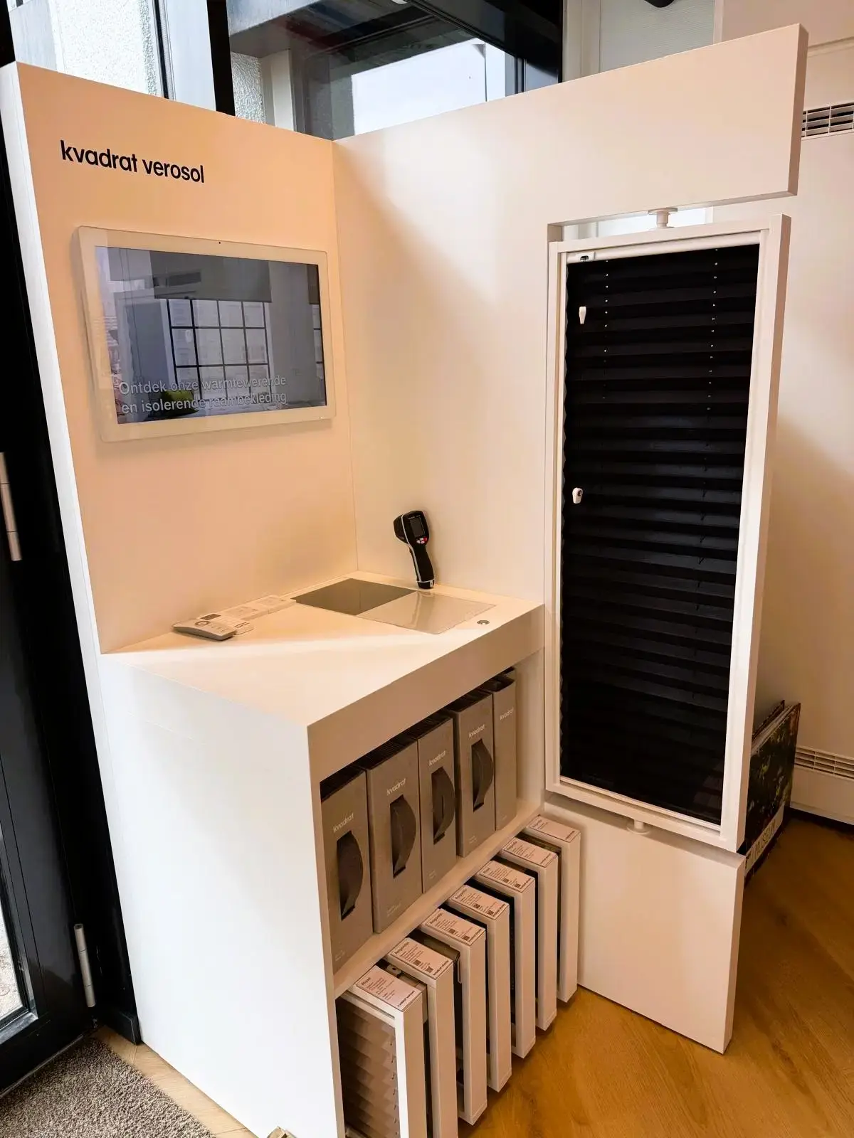 Presentatie met een plissé in een kozijn en stalenboeken eronder, in de showroom van Leeuwenkamp