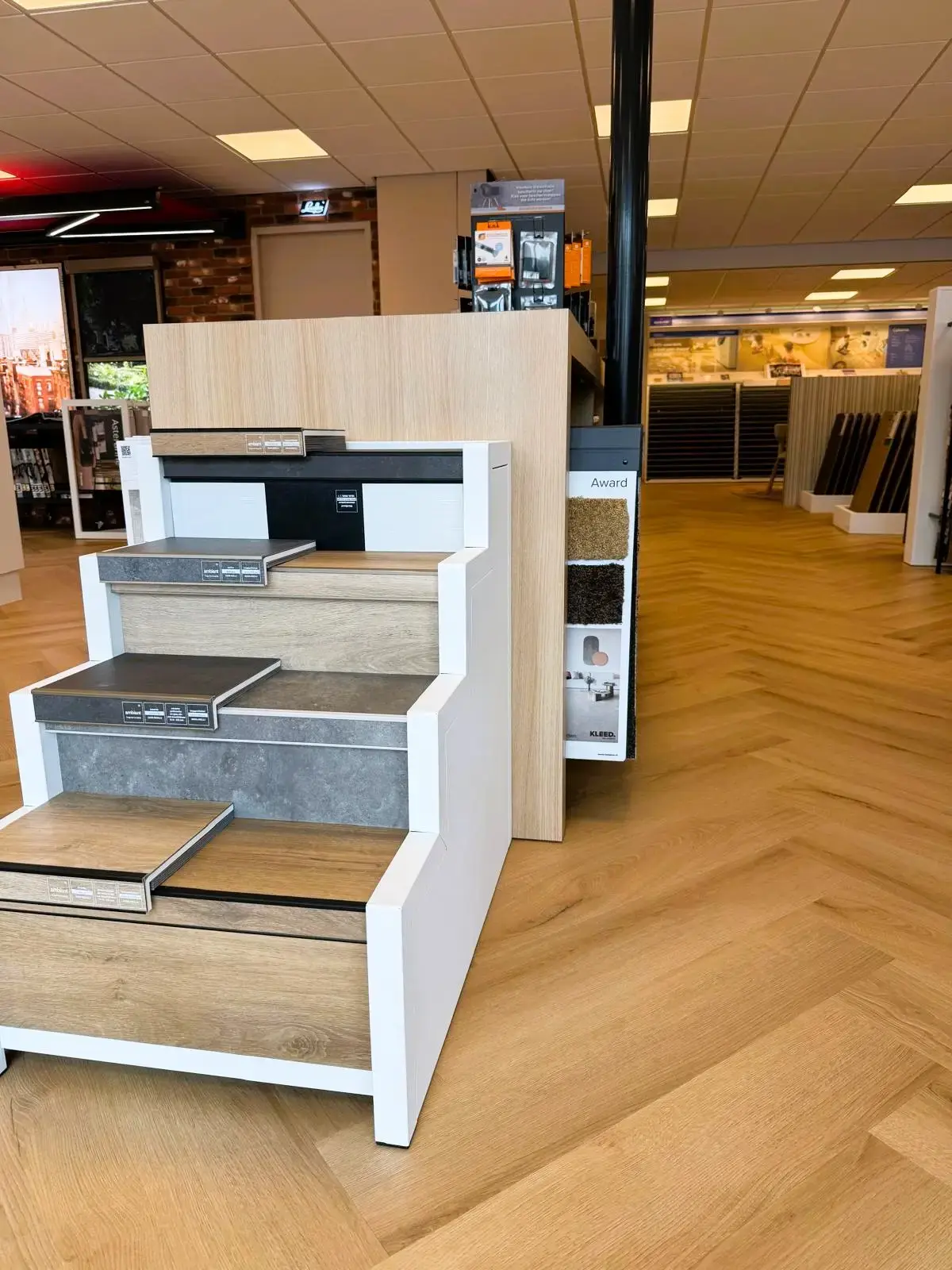 Showroomtrap met treden in hout- en steenlook naast tapijtstalen, bij Leeuwenkamp