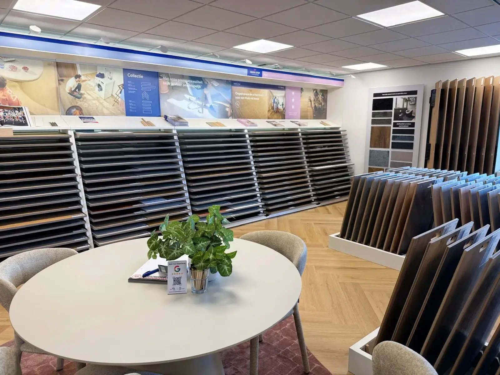 Vloerenafdeling in de showroom van Leeuwenkamp, met wanden vol PVC- en laminaatstalen en een ronde adviestafel