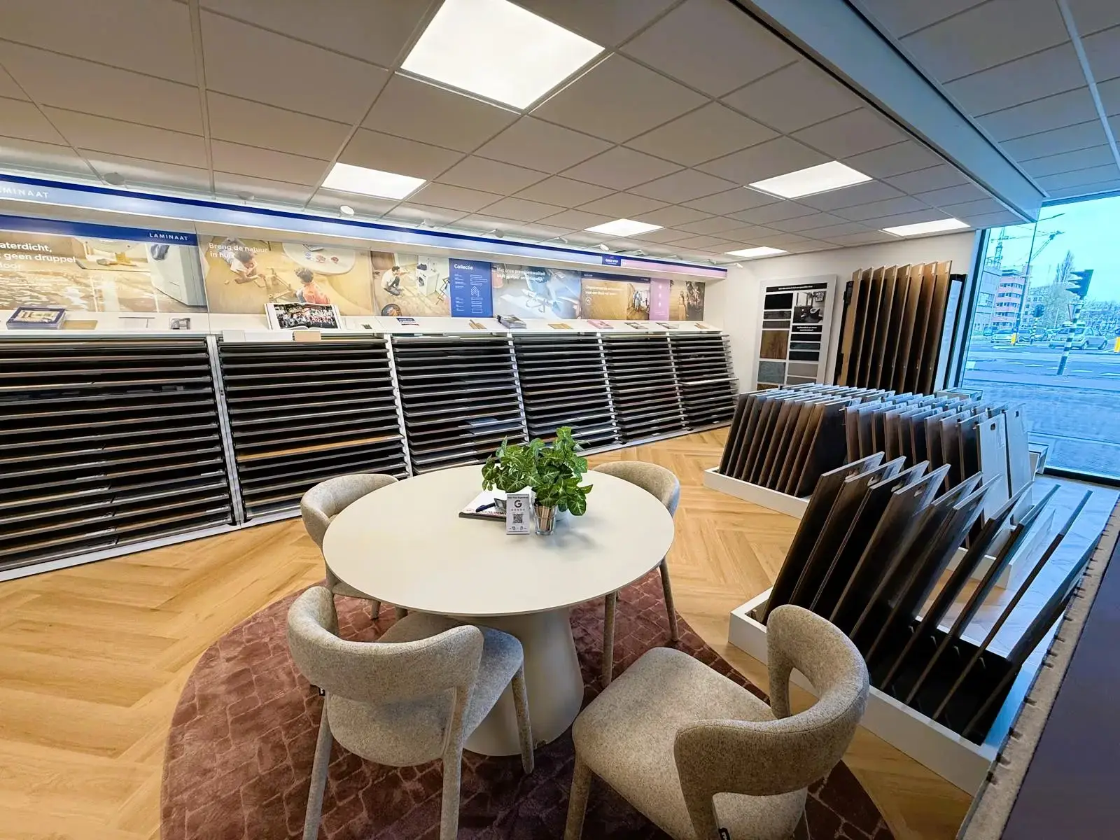 Ronde adviestafel in de showroom van Leeuwenkamp, voor een lange wand met laminaat- en PVC-stalen